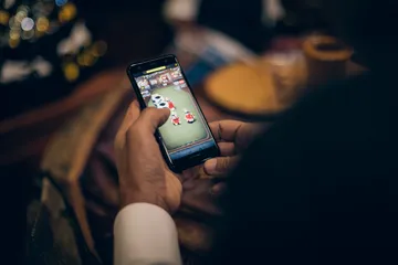 A man celebrating a winning moment on his laptop while gaming symbols float around him, capturing the excitement of HI76 games.